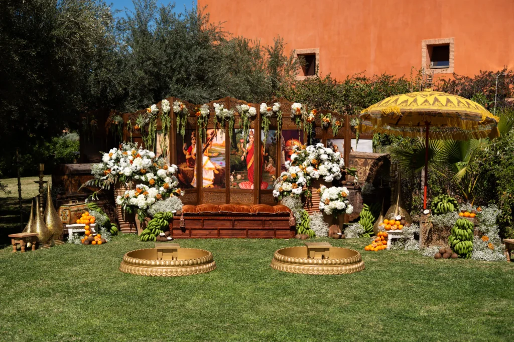 Outdoor ceremony décor with floral arch and Moroccan parasols on a lawn, Marrakesh destination wedding