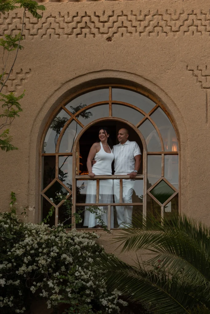 Bride and groom framed in an arched riad window surrounded by greenery, Marrakesh destination wedding