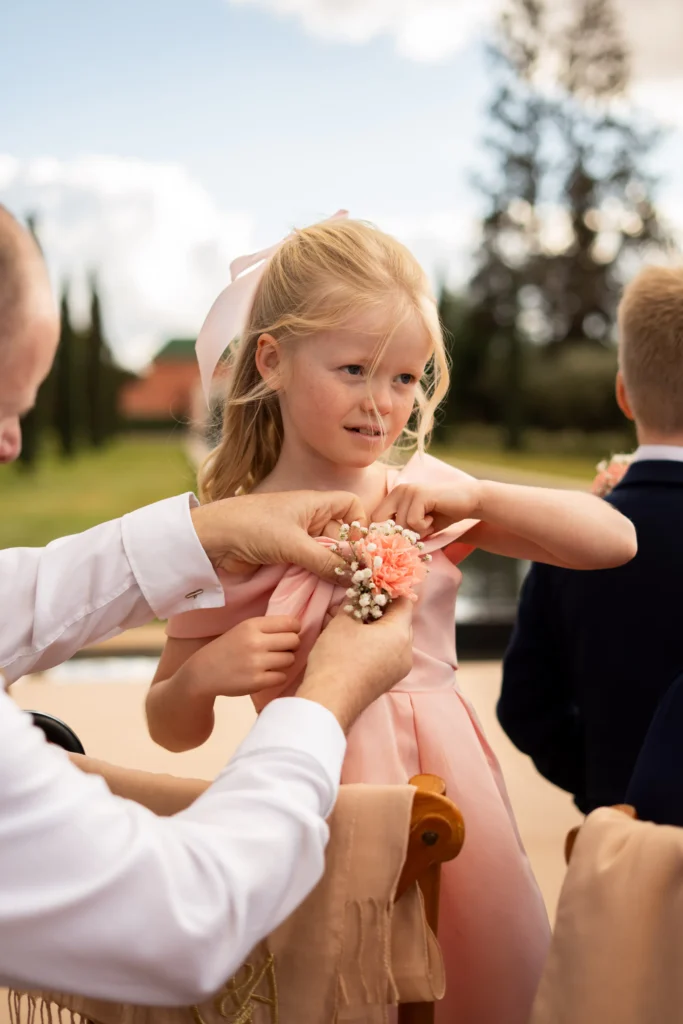 Flower girl having a floral wrist corsage tied on at a Marrakesh destination wedding