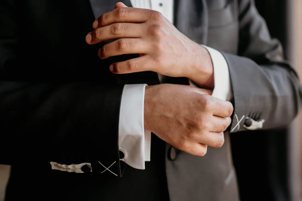 Groom fastening his cufflink in a grey suit, luxury Morocco destination wedding detail photography