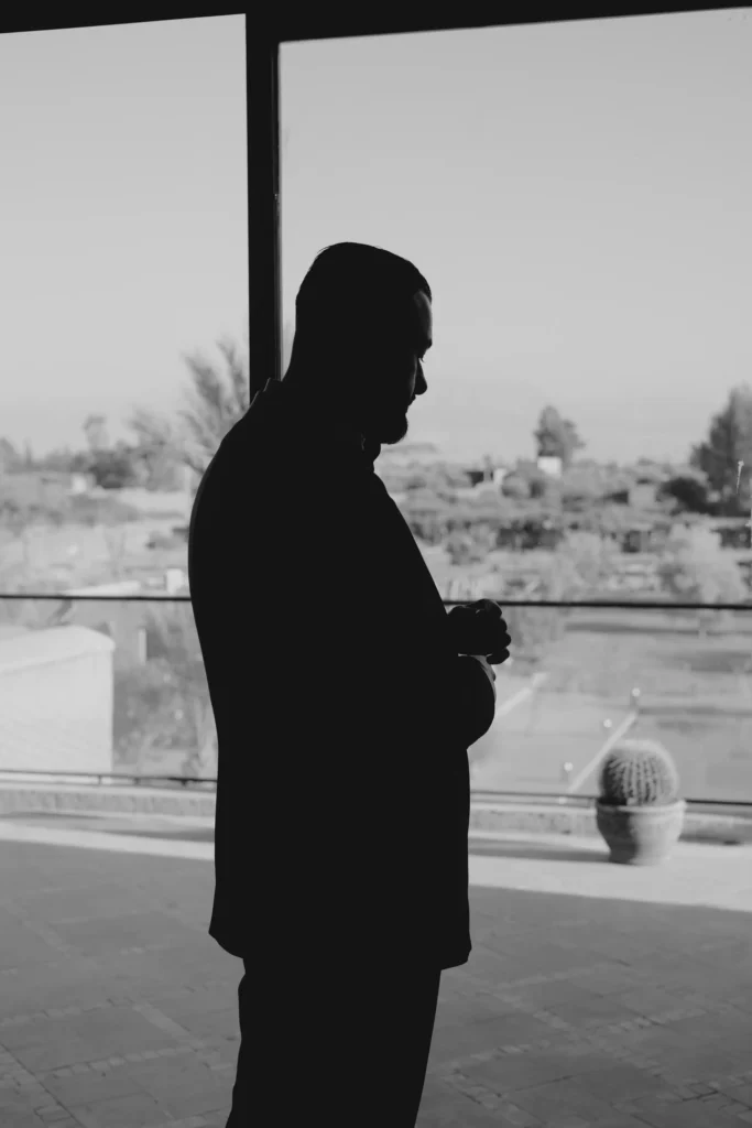Silhouette of a groom by a window overlooking Marrakesh rooftops, black and white destination wedding