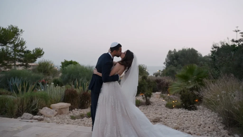 Bride and groom kissing in a misty garden at dusk, romantic Marrakesh Jewish destination wedding