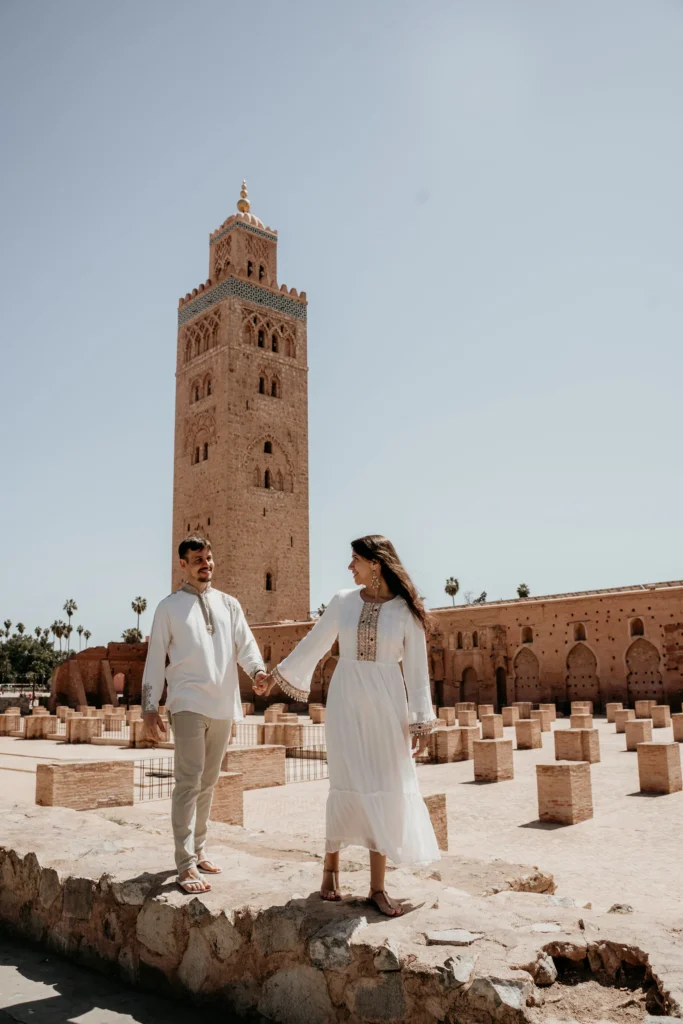 ride and groom in white in front of the Koutoubia Mosque, Marrakesh destination wedding photography