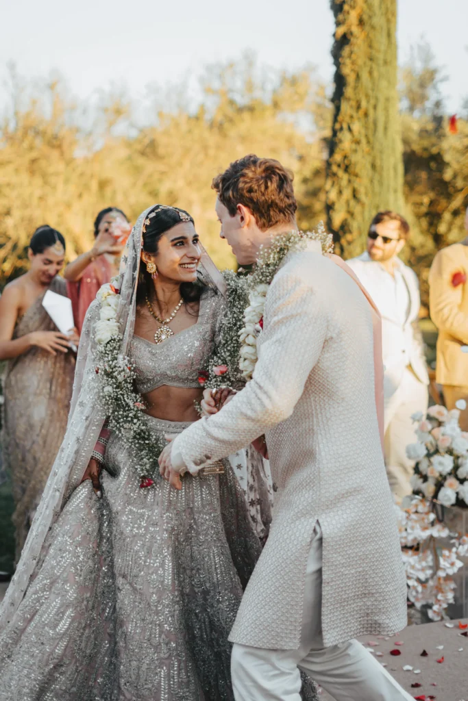 Indian bride and groom exchanging garlands at their outdoor Marrakesh destination wedding ceremony