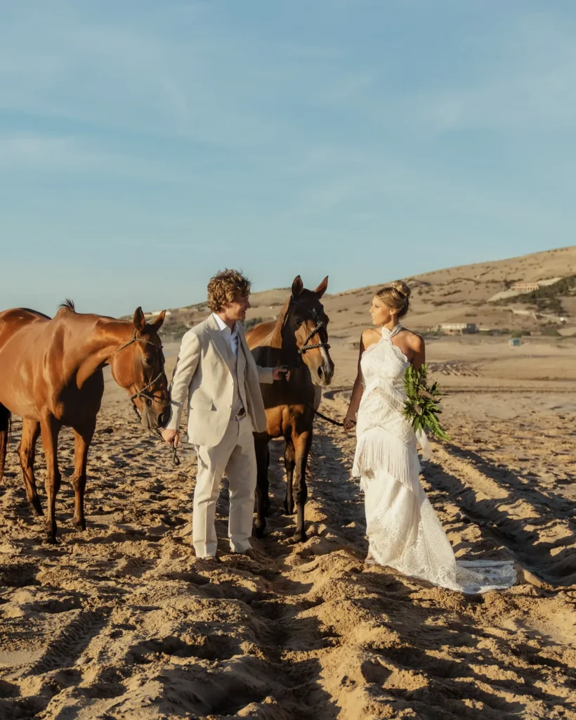 Bride and groom with horses on Essaouira beach at sunset, Morocco destination wedding photography